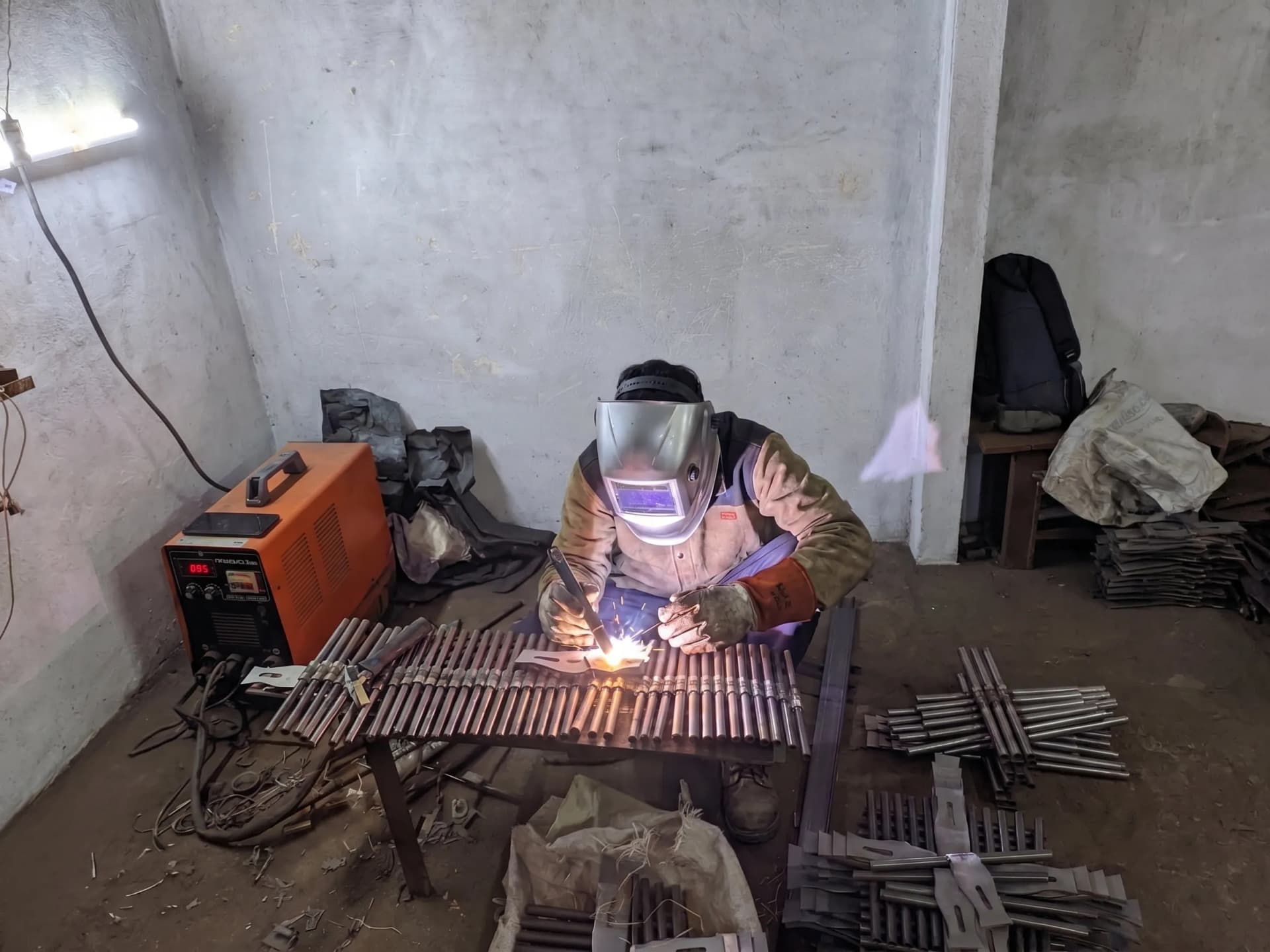 Welder joining iron hardware components amid sparks at the Nexus Fittings factory floor in Aligarh